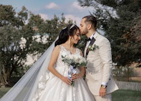 A romantic outdoor portrait of a bride and groom sharing a tender moment on their wedding day.
